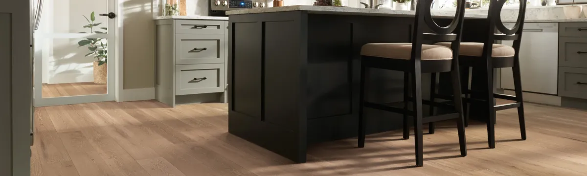 Kitchen scene - light wood-look floors, kitchen island with two stools.