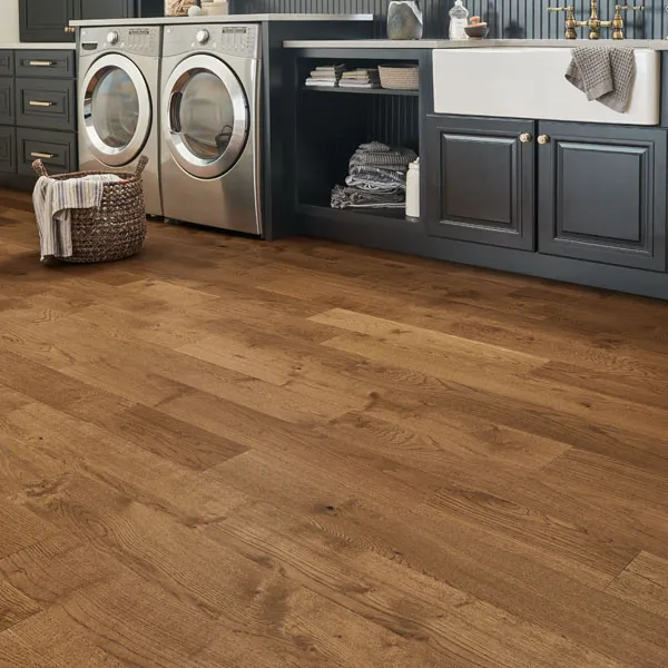 Entryway scene - Boots and shoes by door, small rug in front of door, purse sitting on chest of drawers, laminate flooring.